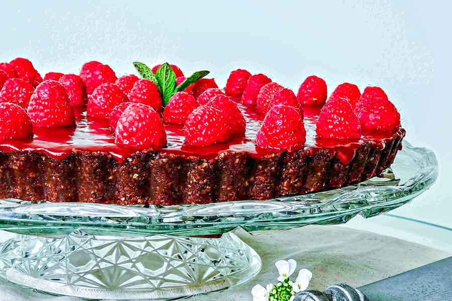 raspberry chocolate tart on a cake platter