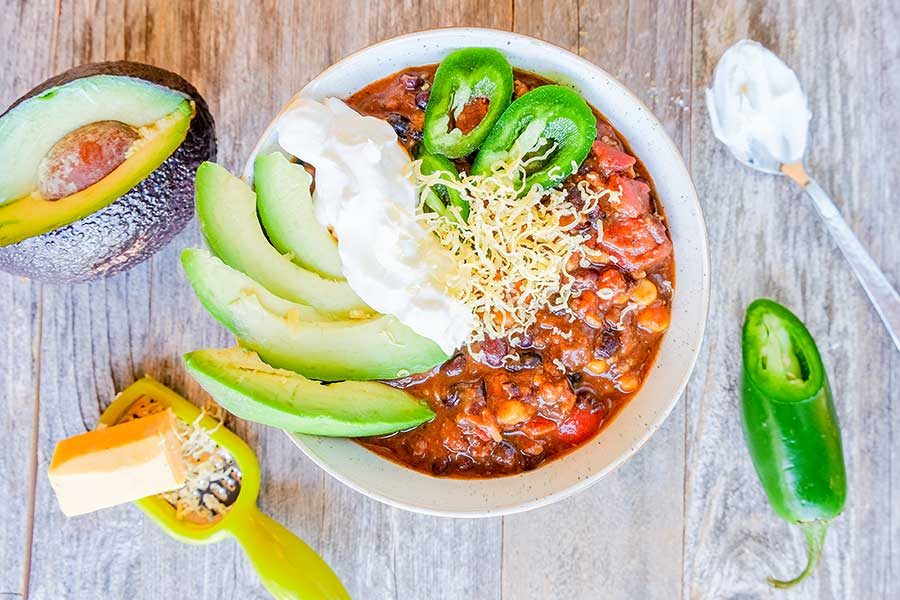chili in a bowl with avocado and sourcream topping