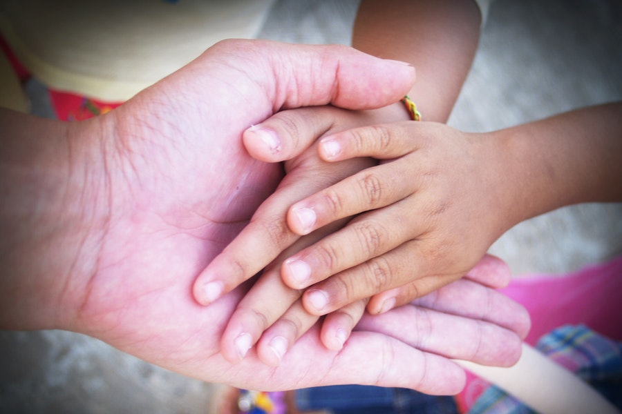 adult hand and 2 children's hands holding together