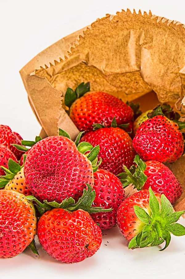 strawberries spilling from a paper bag