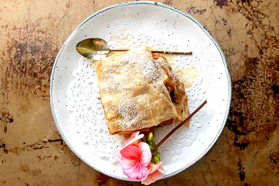 gluten free apple strudel on a plate with a spoon and a flower