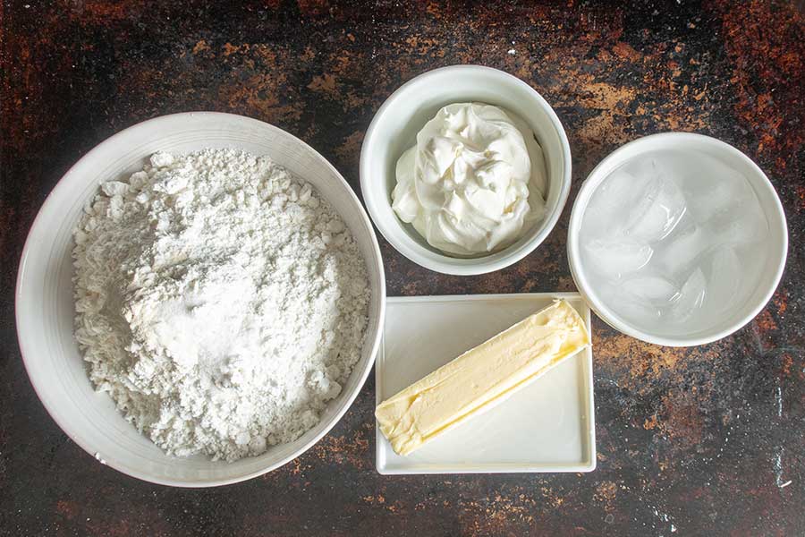 gluten free short crust ingredients in bowls, flour, sour cream, butter, ice water
