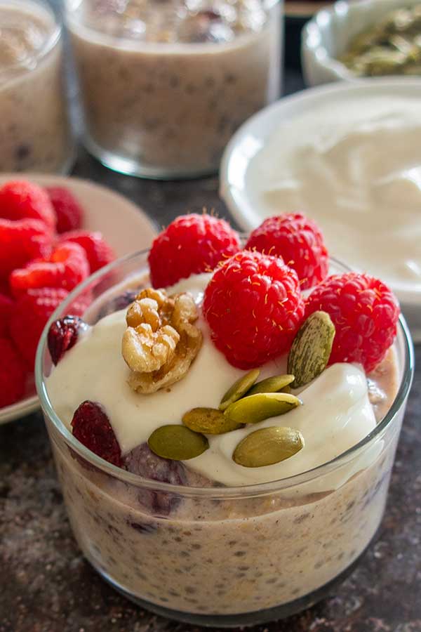 cranberry walnut overnight oats with topping of berries and pumpkin seeds in a jar