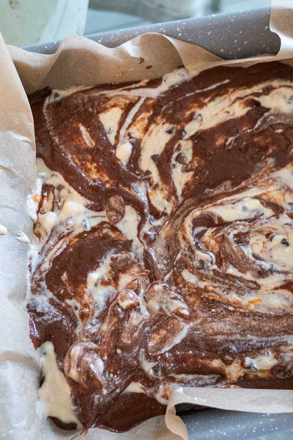 brownie batter with ricotta swirls in a square pan