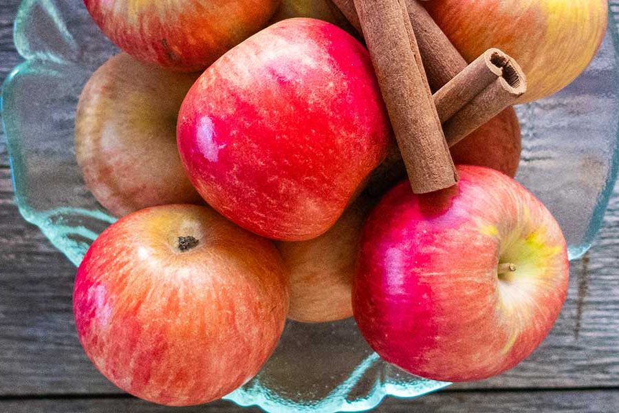 fresh apples and cinnamon sticks in a bowl