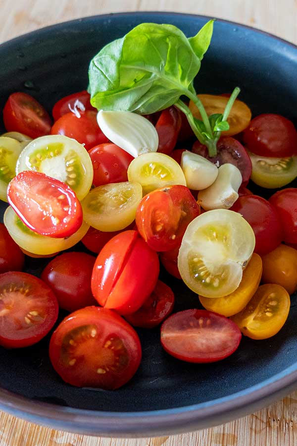 sliced cherry tomatoes, sliced garlic and fresh basil in a bowl