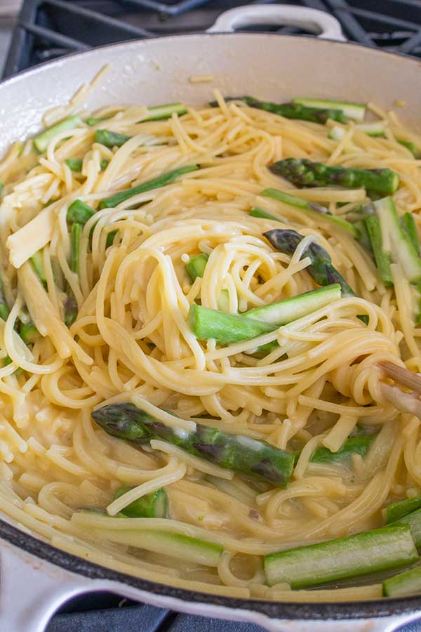 spaghetti and asparagus swirled together in a pan
