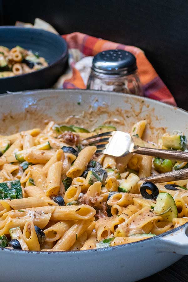 penne in cream sauce with olives in a skillet