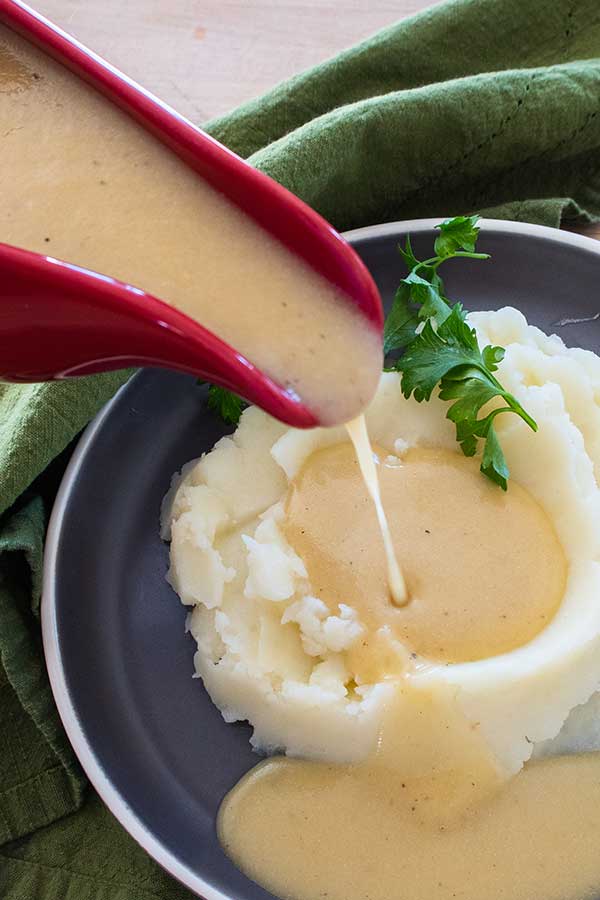 pouring gravy over mashed potatoes